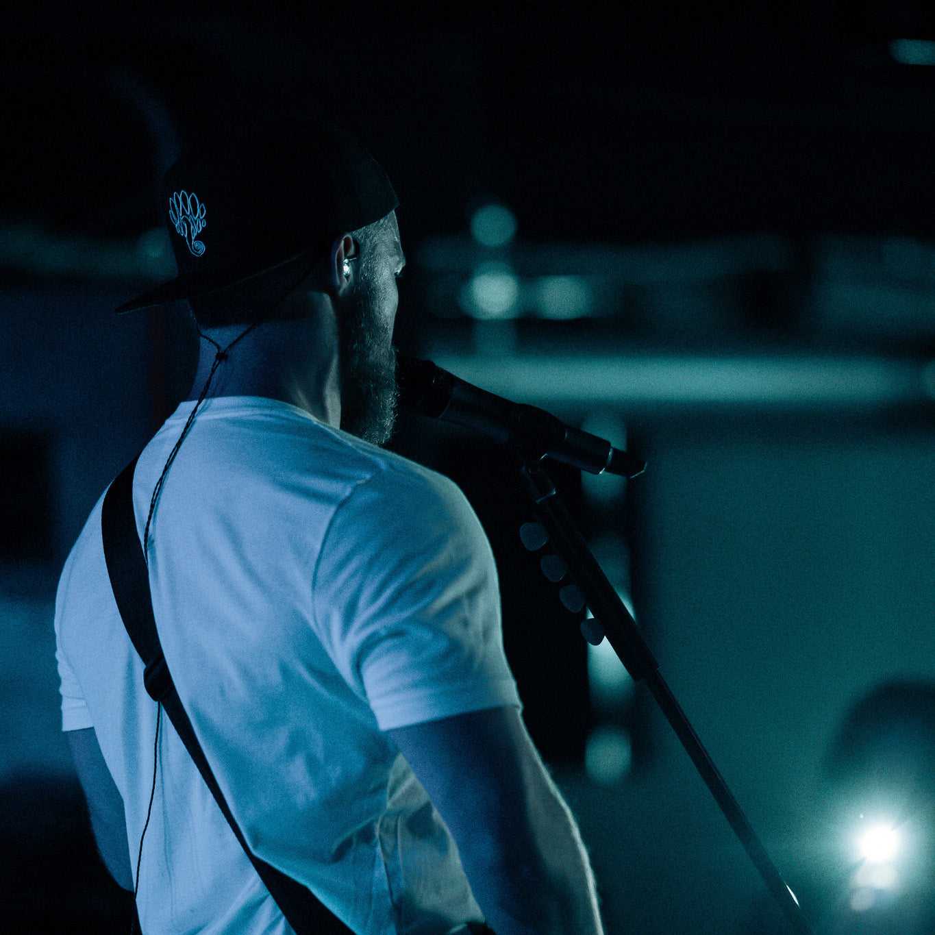 black snapback hat with polokus creature logo on stage musician